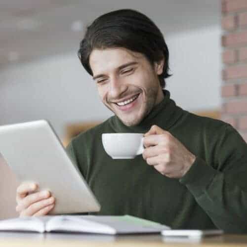 young successful businessman checking emails while having morning coffee e1631573561115